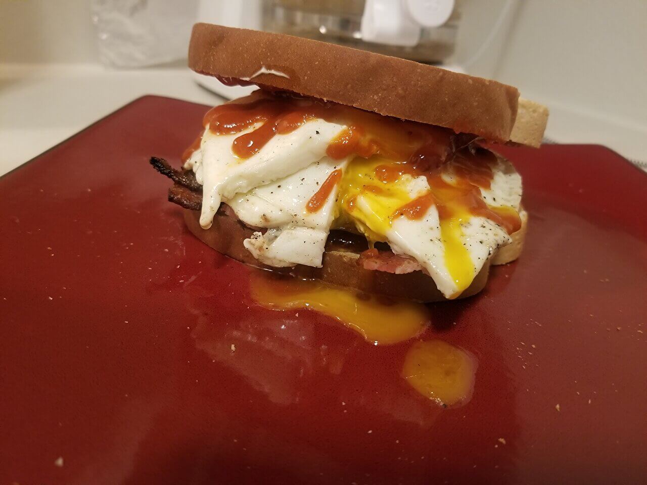 Egg and bacon sandwich with strawberry preserves and sriracha